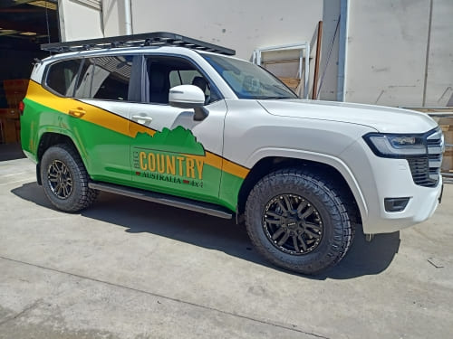 vehicle-custom-signage-perth A white four wheel drive car with green and yellow vehicle signage